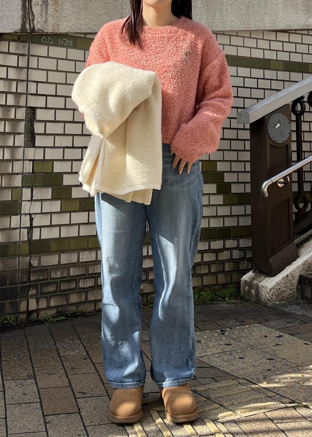 ブルー系のデニムパンツ、ピンク系のニット/セーター、シルバー系のブローチ/コサージュを着用したレディースの冬コーディネートの4枚目の写真