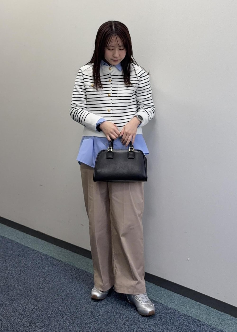 シルバー系のスニーカー、ブラック系のボストンバッグ、ベージュ系のチノパンツを着用したレディースの冬コーディネートの3枚目の写真