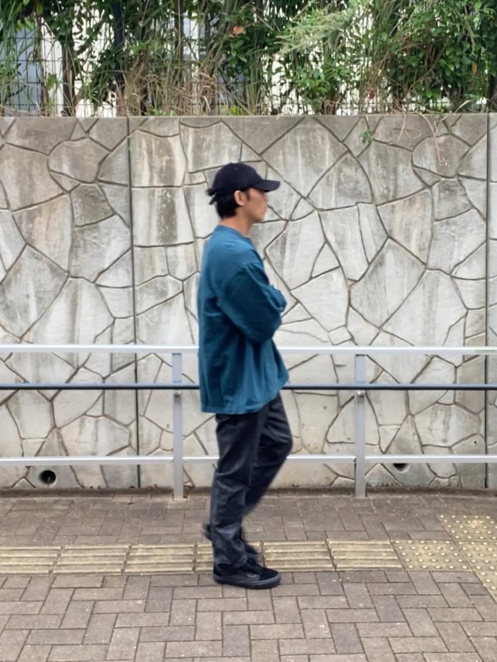 グリーン系のスウェット、ブラック系のデニムパンツ、ブラック系のスニーカーを着用したメンズの秋コーディネートの2枚目の写真