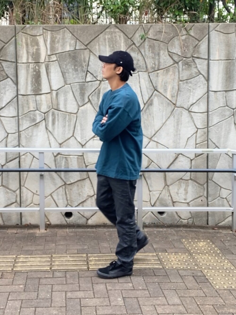 グリーン系のスウェット、ブラック系のデニムパンツ、ブラック系のスニーカーを着用したメンズの秋コーディネートの3枚目の写真