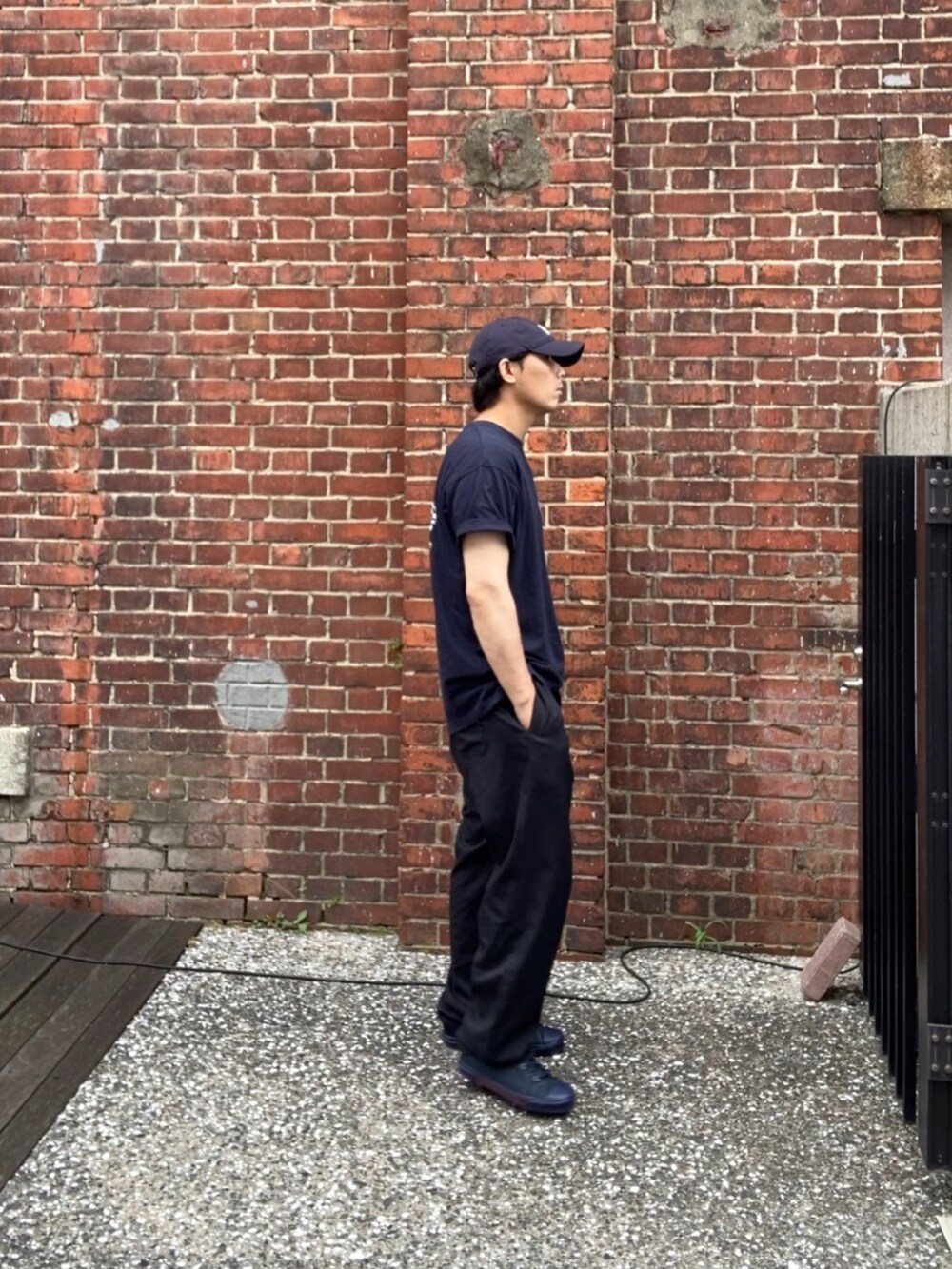 ブルー系のTシャツ/カットソー、ブラック系のスラックス、ブルー系のスニーカーを着用したメンズの夏コーディネートの3枚目の写真