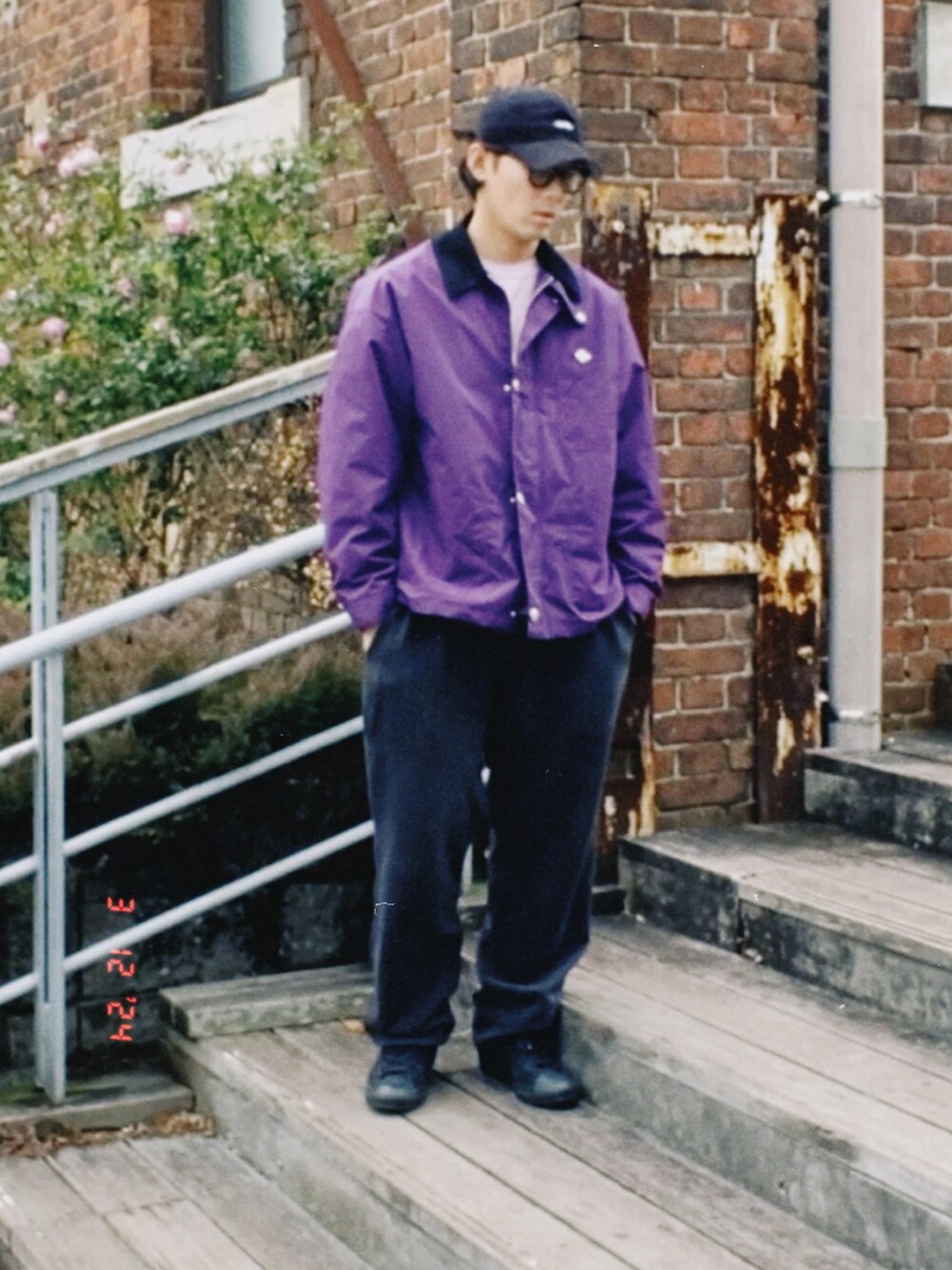 パープル系のカバーオール、パープル系のスウェット、ブラック系のスウェットパンツを着用したメンズの春コーディネートの3枚目の写真