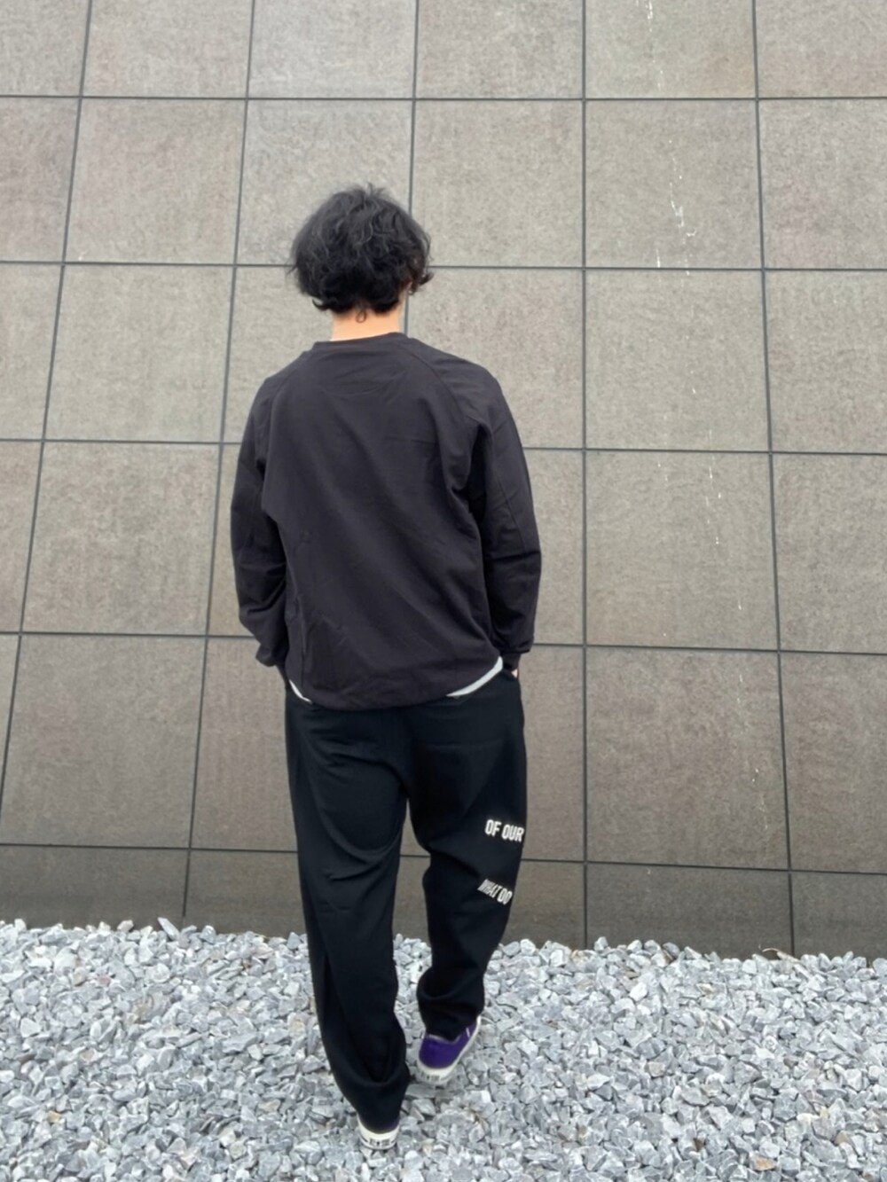 ブラック系のスウェット、ブラック系のスラックス、パープル系のスニーカーを着用したメンズの春コーディネートの4枚目の写真