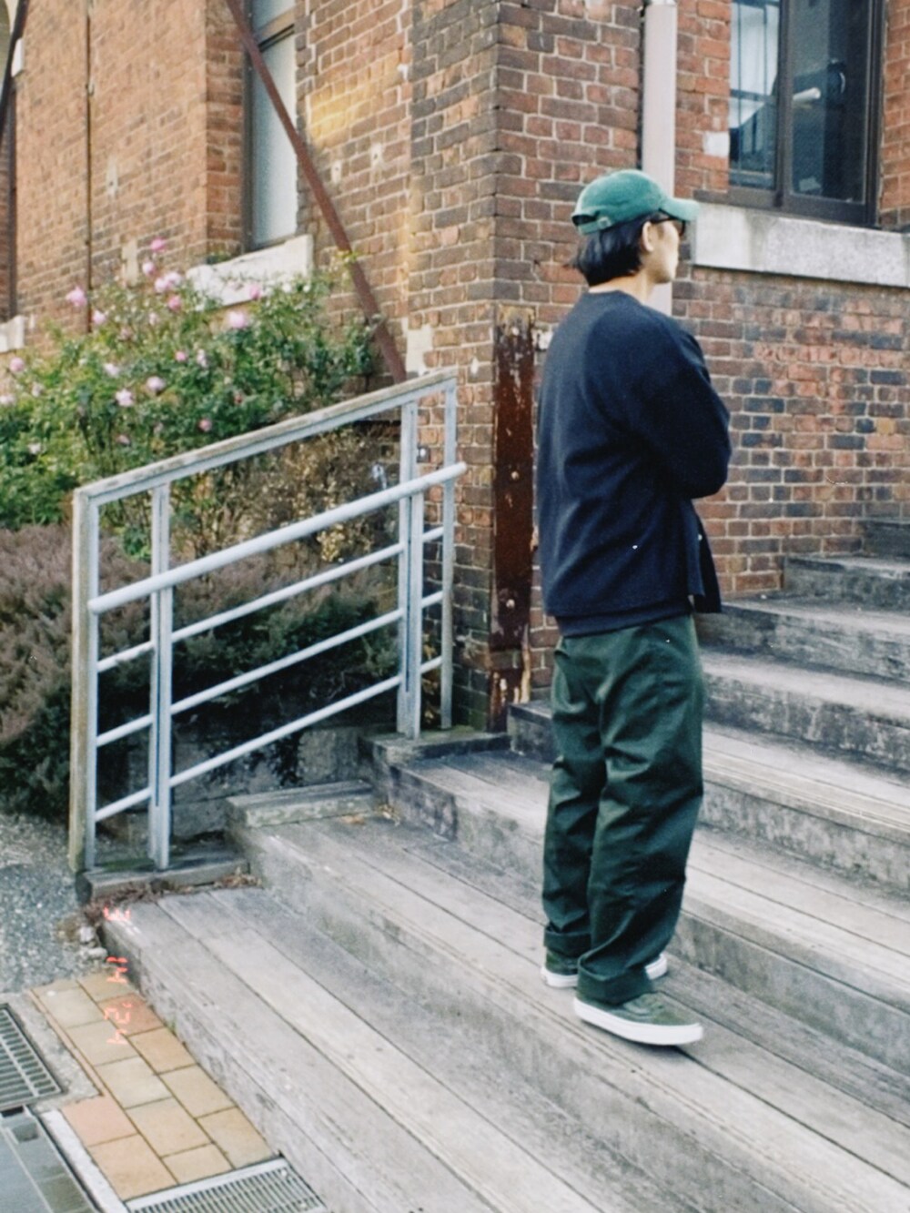 ブラック系のカーディガン/ボレロ、ブラック系のTシャツ/カットソー、グリーン系のチノパンツを着用したメンズの春コーディネートの3枚目の写真