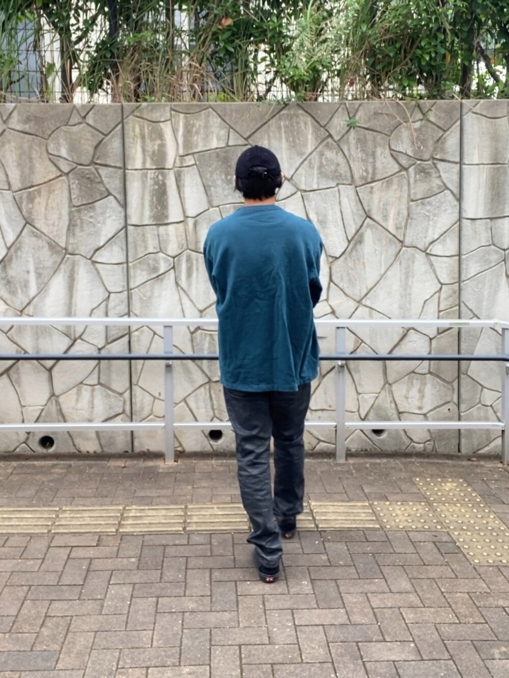 グリーン系のスウェット、ブラック系のデニムパンツ、ブラック系のスニーカーを着用したメンズの秋コーディネートの4枚目の写真