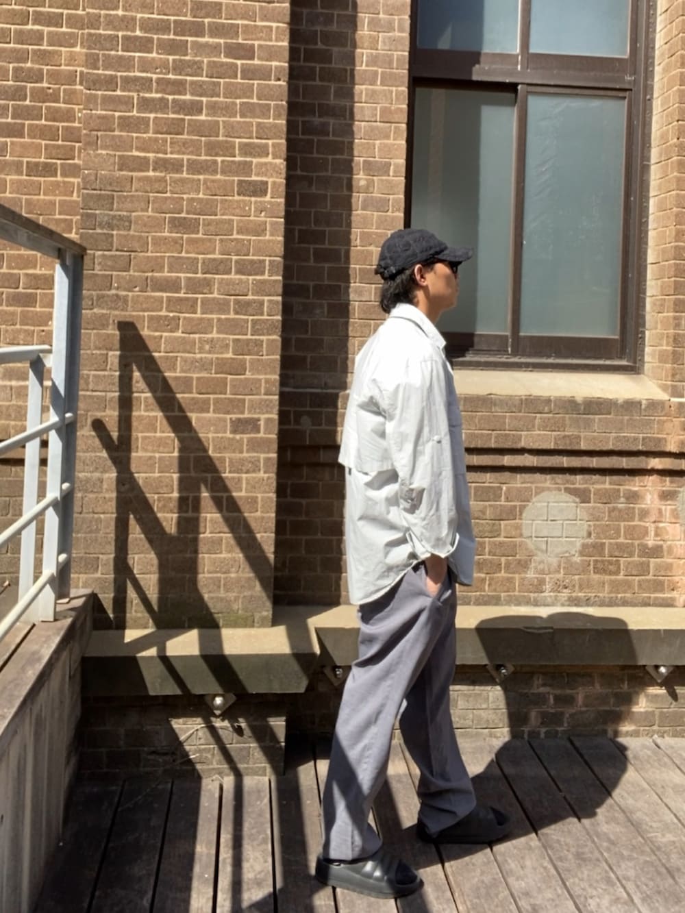 グレー系のスラックス、ブラック系のサンダル、ブラック系のタンクトップを着用したメンズの夏コーディネートの3枚目の写真