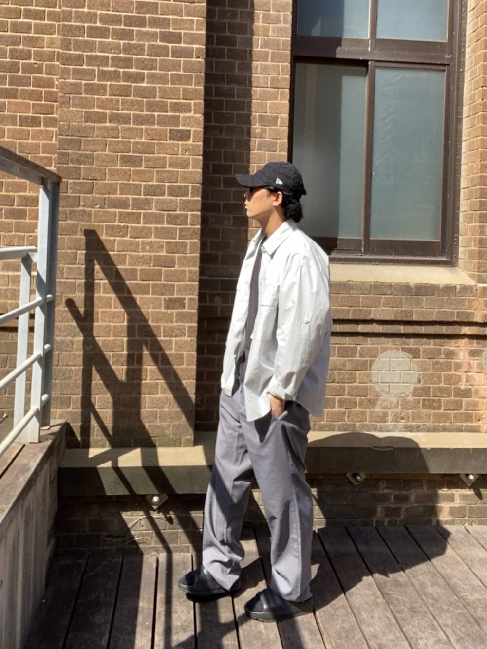 グレー系のスラックス、ブラック系のサンダル、ブラック系のタンクトップを着用したメンズの夏コーディネートの2枚目の写真