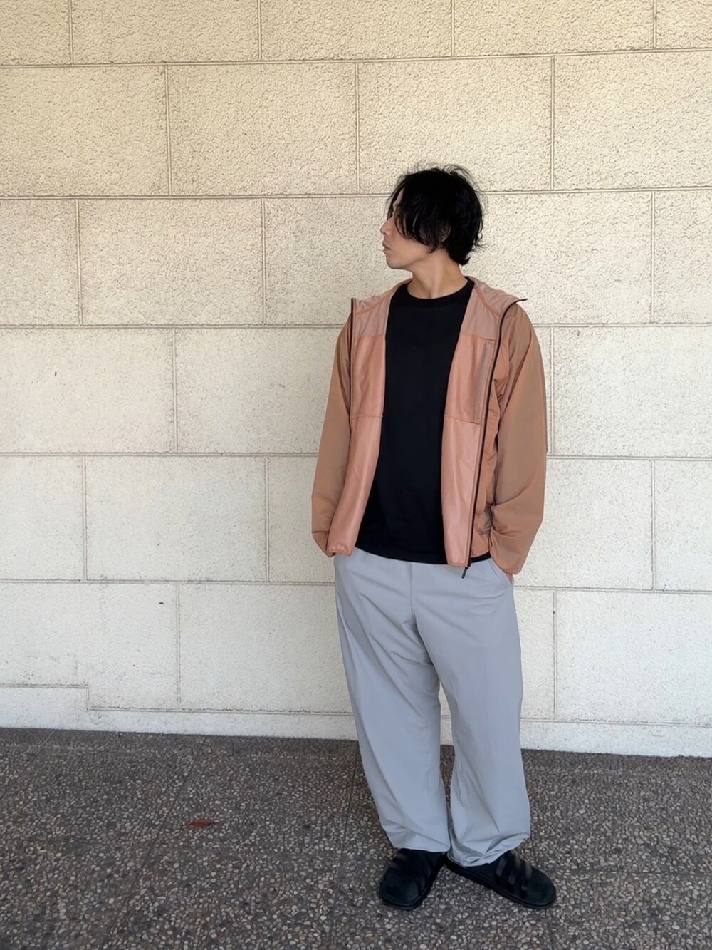 ブラック系のTシャツ/カットソー、オレンジ系のナイロンジャケット、グレー系のその他パンツを着用したメンズの春コーディネートの2枚目の写真