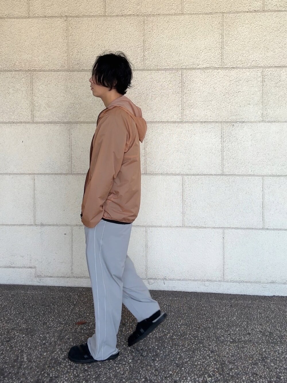 ブラック系のTシャツ/カットソー、オレンジ系のナイロンジャケット、グレー系のその他パンツを着用したメンズの春コーディネートの3枚目の写真