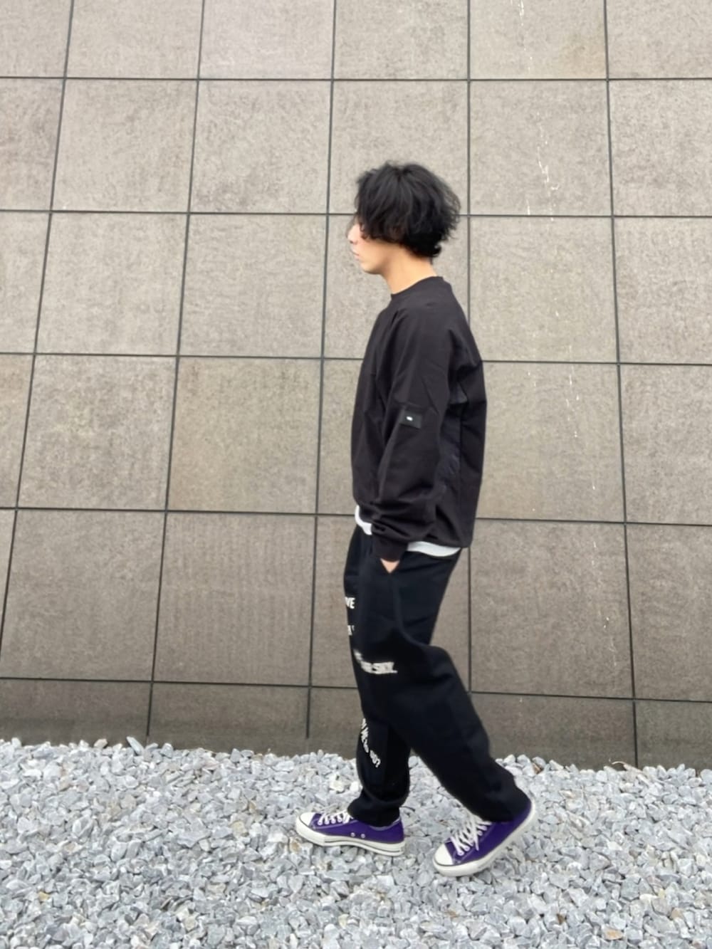 ブラック系のスウェット、ブラック系のスラックス、パープル系のスニーカーを着用したメンズの春コーディネートの3枚目の写真