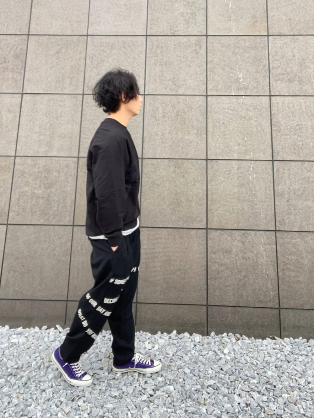 ブラック系のスウェット、ブラック系のスラックス、パープル系のスニーカーを着用したメンズの春コーディネートの2枚目の写真