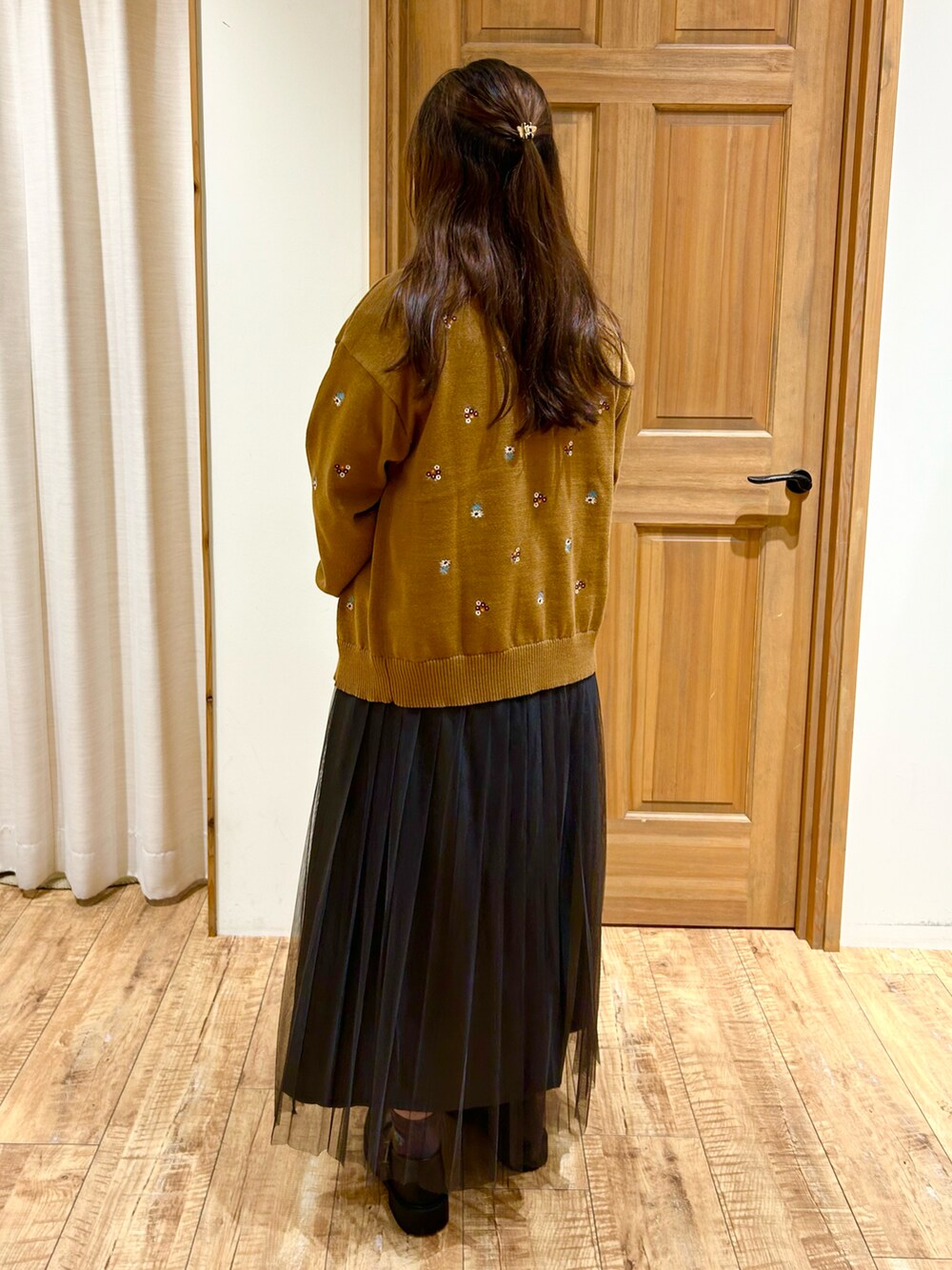 イエロー系のカーディガン/ボレロ、ホワイト系のTシャツ/カットソー、グレー系のスカートを着用したレディースの秋コーディネートの4枚目の写真