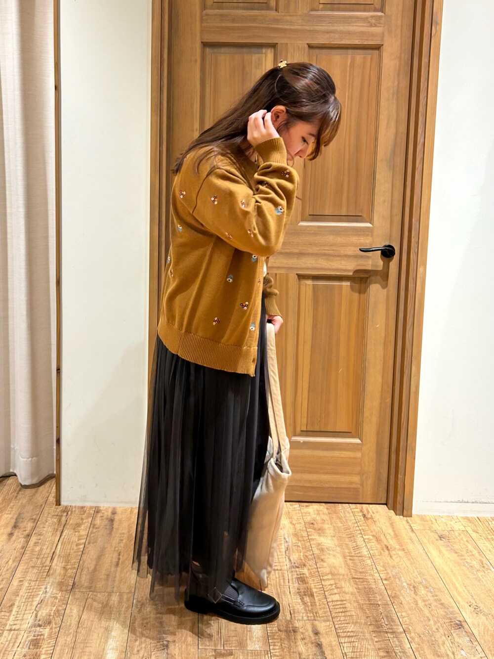 イエロー系のカーディガン/ボレロ、ホワイト系のTシャツ/カットソー、グレー系のスカートを着用したレディースの秋コーディネートの3枚目の写真