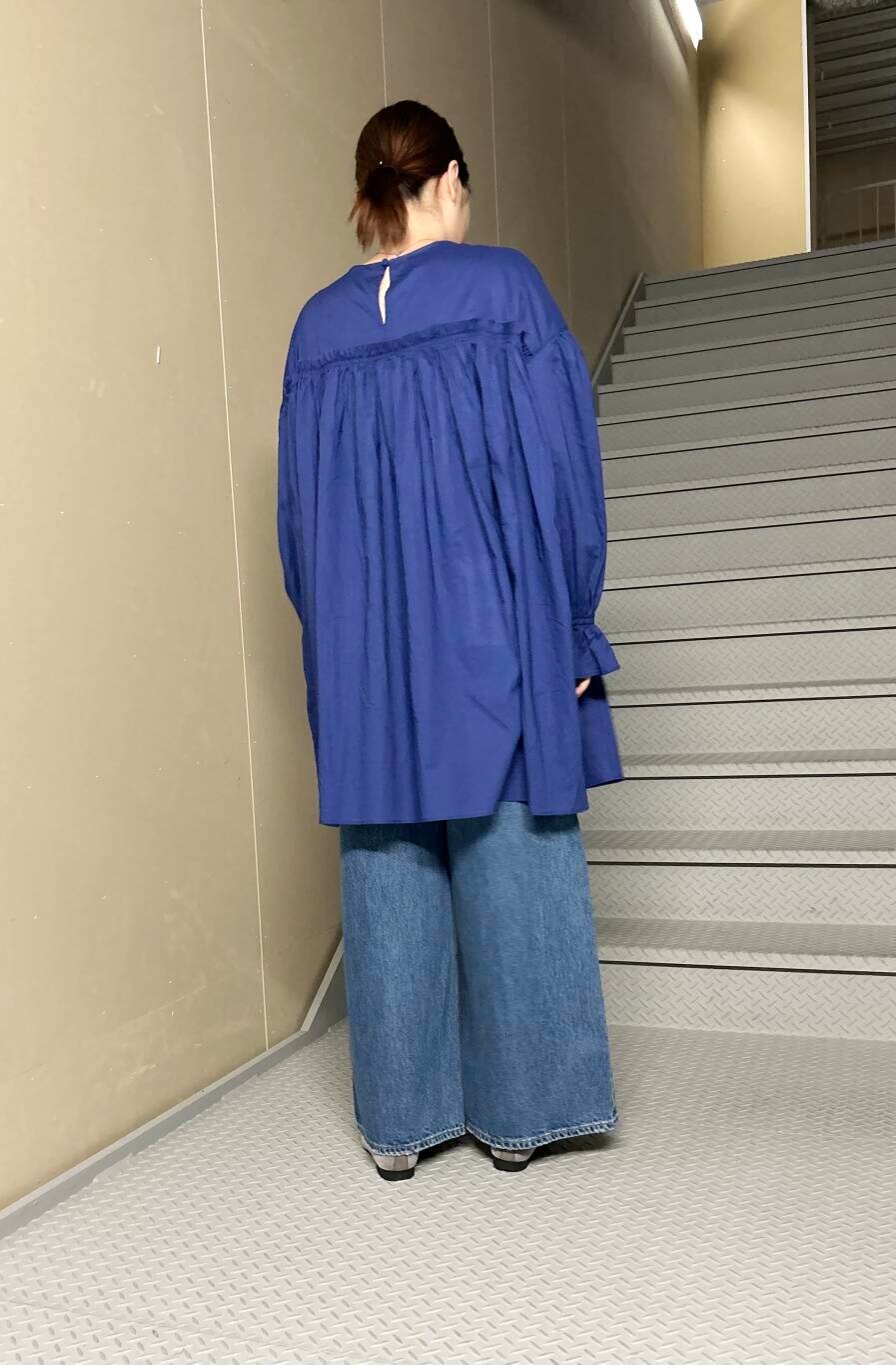 ブルー系のデニムパンツ、ブルー系のチュニック、グレー系のバレエシューズを着用したレディースの夏コーディネートの3枚目の写真