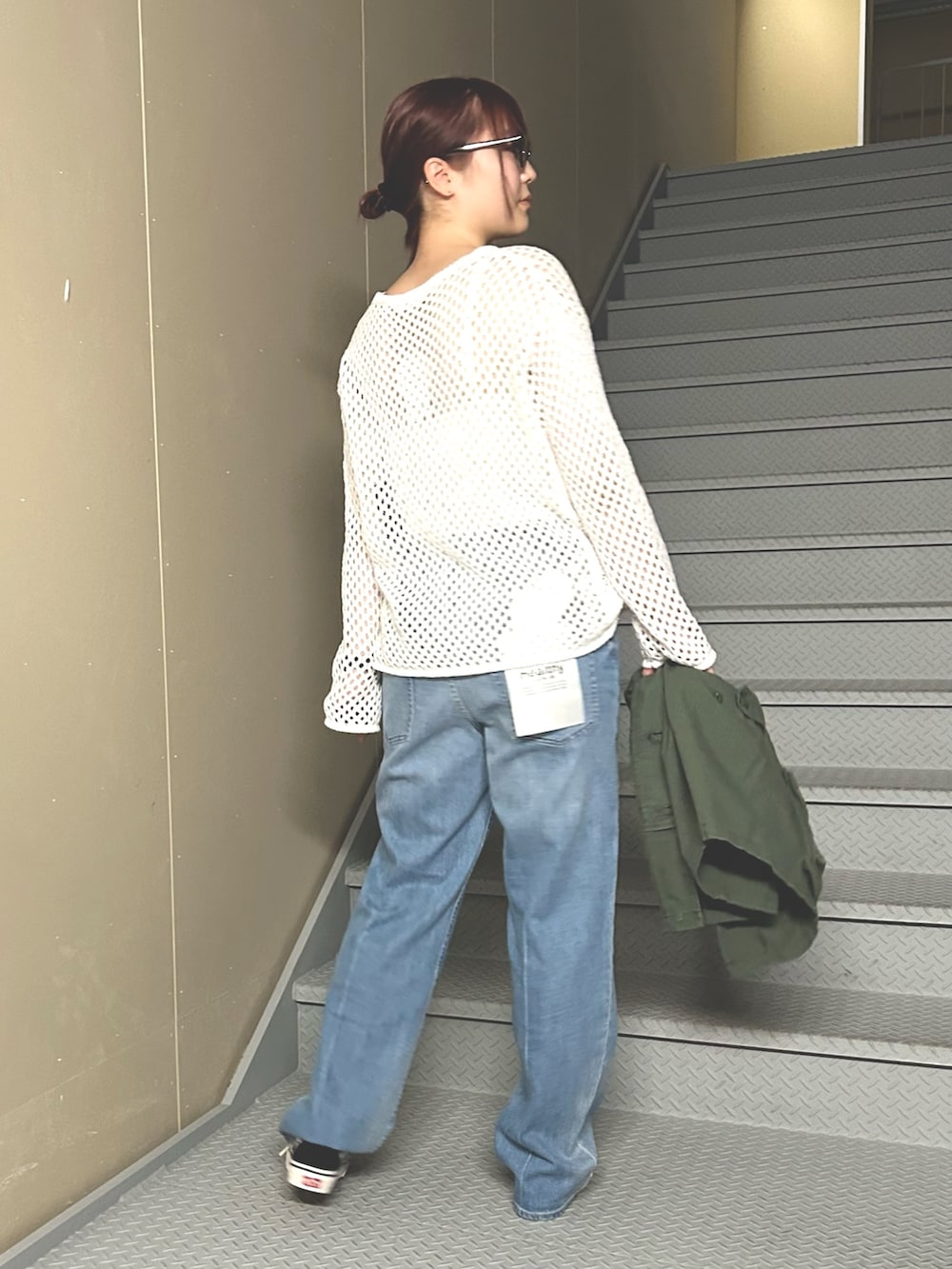 ブルー系のデニムパンツ、ホワイト系のニット/セーター、グリーン系のベストを着用したレディースの冬コーディネートの2枚目の写真