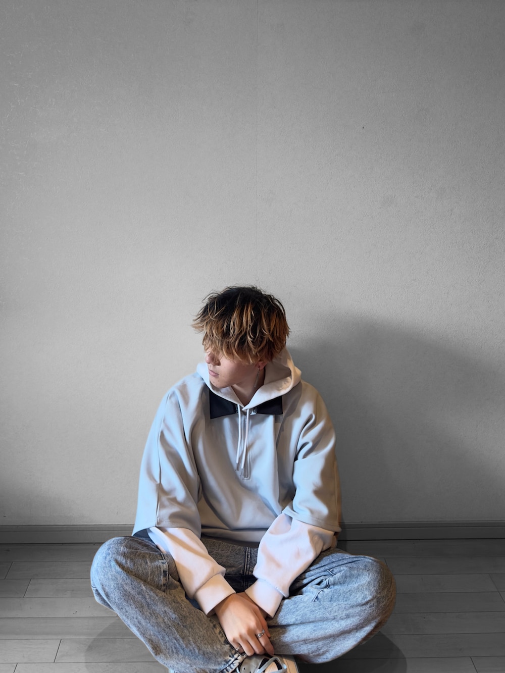 ホワイト系のパーカー、グレー系のポロシャツ、ブルー系のデニムパンツを着用したメンズの冬コーディネートの2枚目の写真