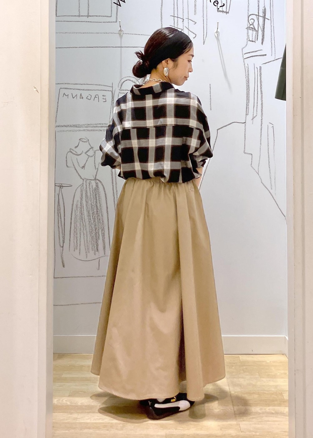 レッド系のトートバッグ、ブラック系のシャツ/ブラウス、ベージュ系のスカートを着用したレディースの秋コーディネートの2枚目の写真