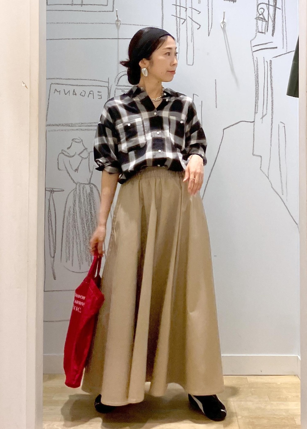 レッド系のトートバッグ、ブラック系のシャツ/ブラウス、ベージュ系のスカートを着用したレディースの秋コーディネートの5枚目の写真