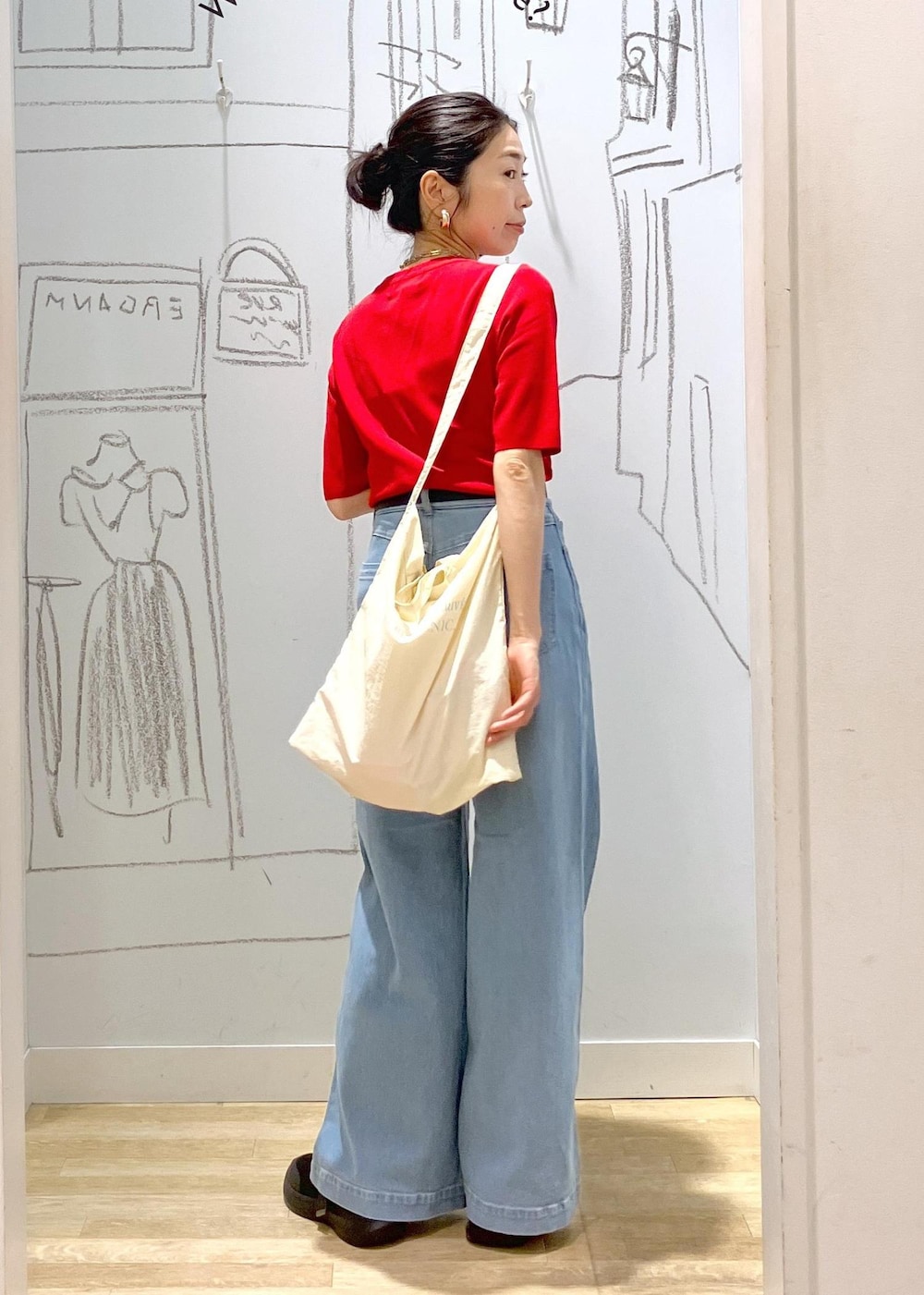 ブルー系のデニムパンツ、ブラック系のスニーカー、ホワイト系のトートバッグを着用したレディースの夏コーディネートの3枚目の写真