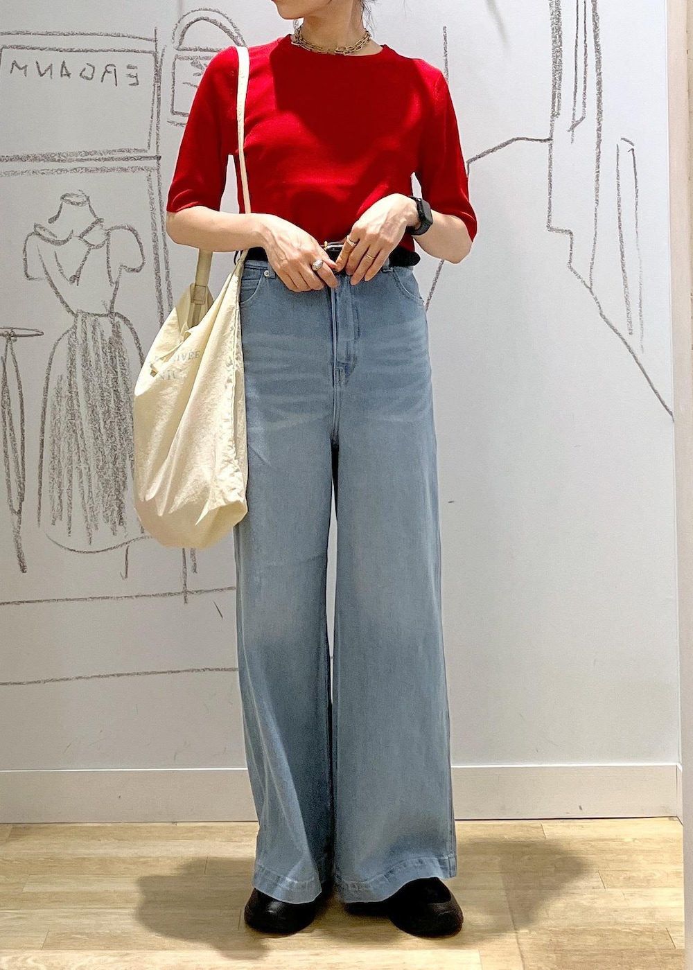 ブルー系のデニムパンツ、ブラック系のスニーカー、ホワイト系のトートバッグを着用したレディースの夏コーディネートの6枚目の写真