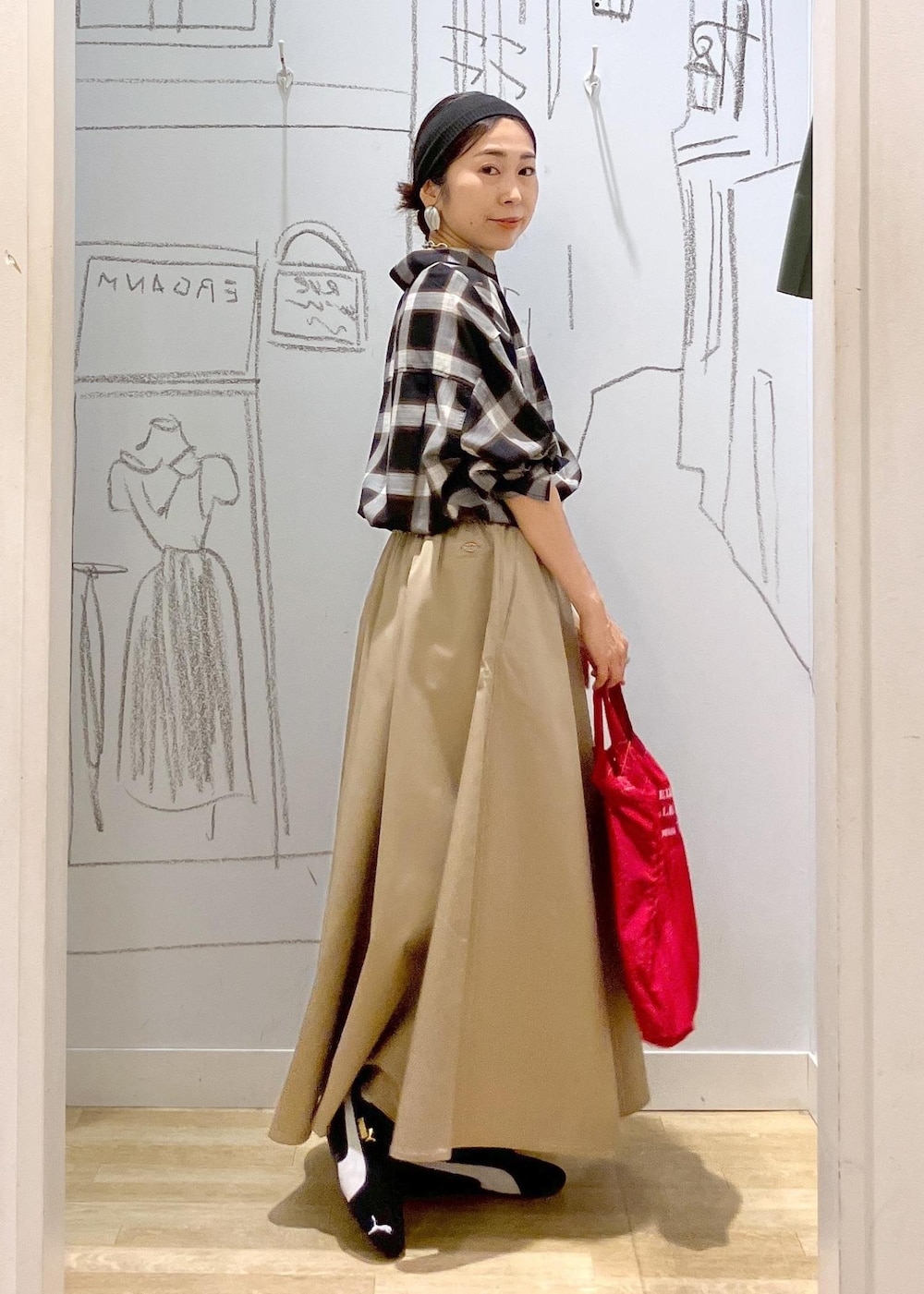 レッド系のトートバッグ、ブラック系のシャツ/ブラウス、ベージュ系のスカートを着用したレディースの秋コーディネートの4枚目の写真