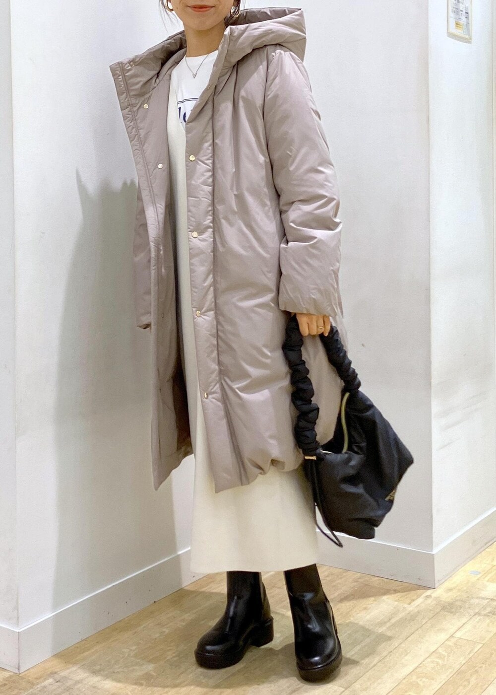 ブラック系のブーツ、ホワイト系のジャンパースカート、ホワイト系のTシャツ/カットソーを着用したレディースの冬コーディネートの3枚目の写真