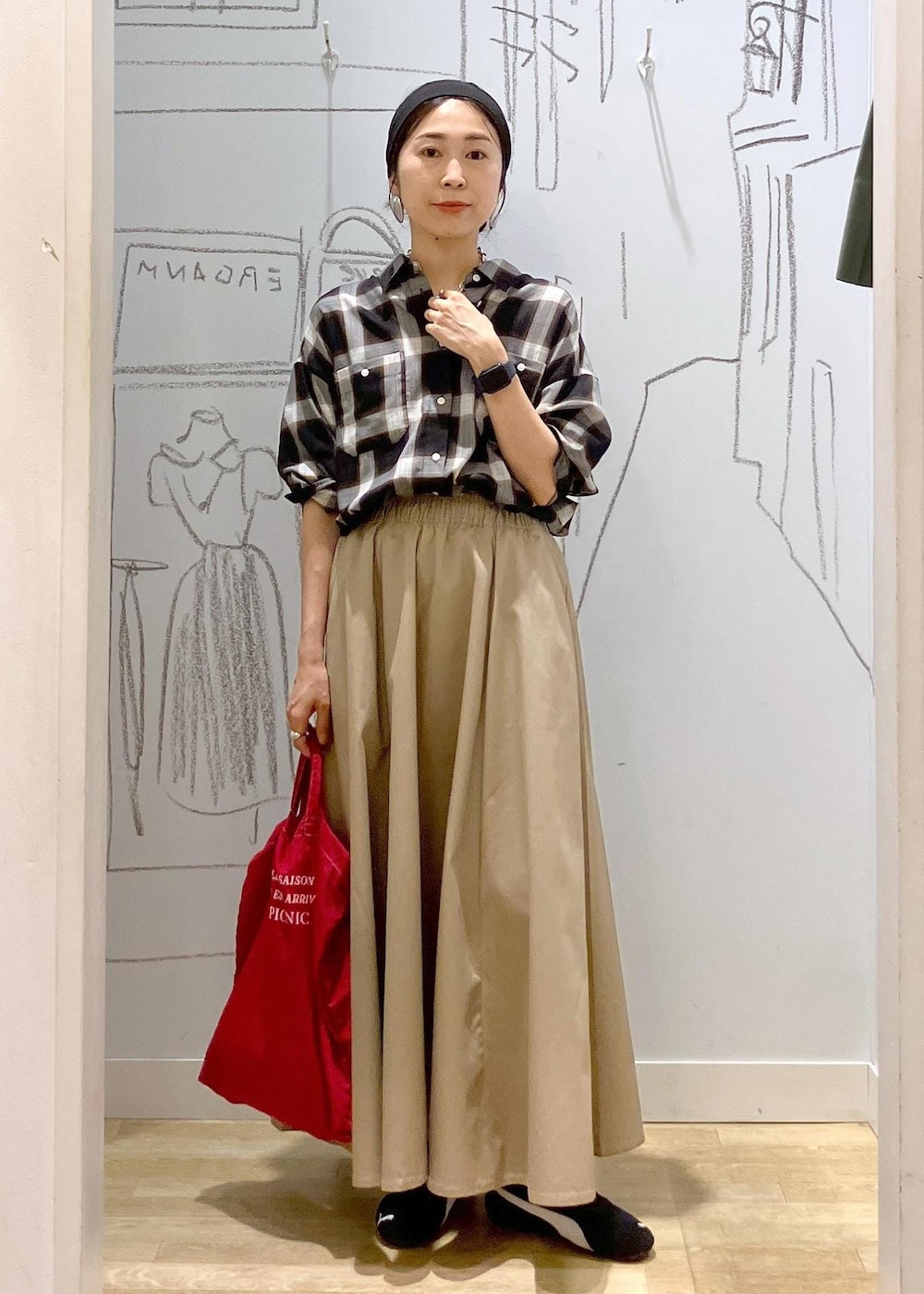 レッド系のトートバッグ、ブラック系のシャツ/ブラウス、ベージュ系のスカートを着用したレディースの秋コーディネートの6枚目の写真