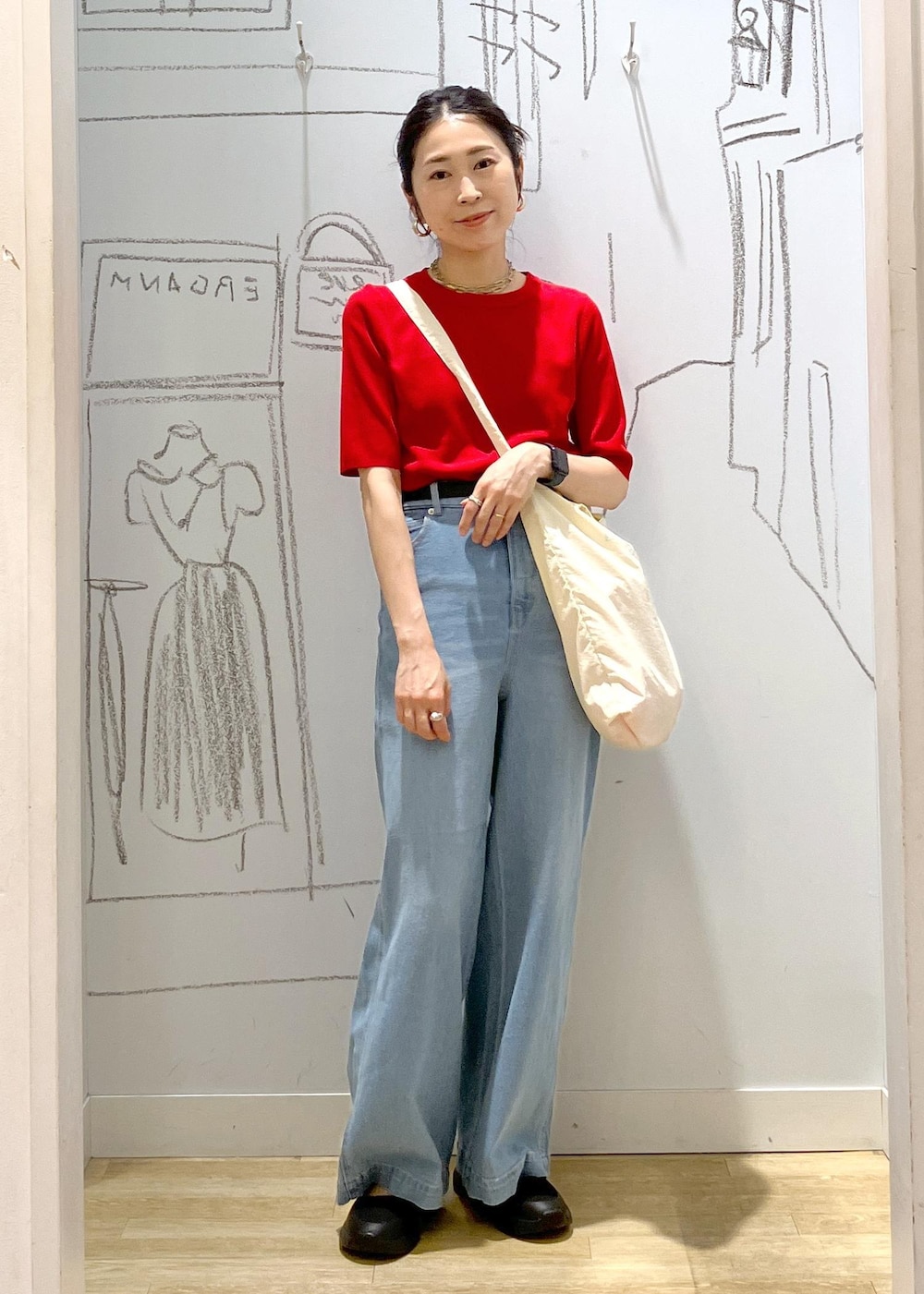 ブルー系のデニムパンツ、ブラック系のスニーカー、ホワイト系のトートバッグを着用したレディースの夏コーディネートの2枚目の写真