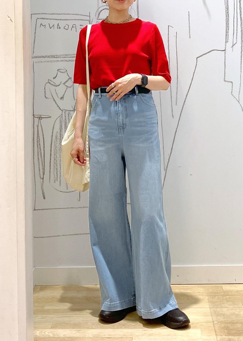 ブルー系のデニムパンツ、ブラック系のスニーカー、ホワイト系のトートバッグを着用したレディースの夏コーディネートの4枚目の写真