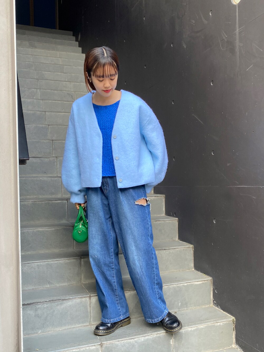 グリーン系のノーカラージャケット、ブルー系のニット/セーター、ブルー系のデニムパンツを着用したレディースの秋コーディネートの2枚目の写真