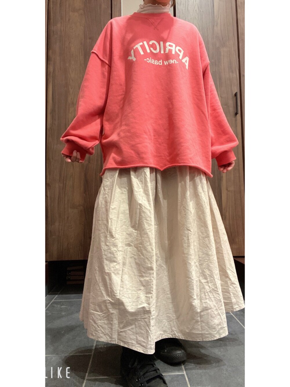 ピンク系のトップス、ホワイト系のスカート、ブラック系のスニーカーを着用したレディースの春コーディネートの3枚目の写真