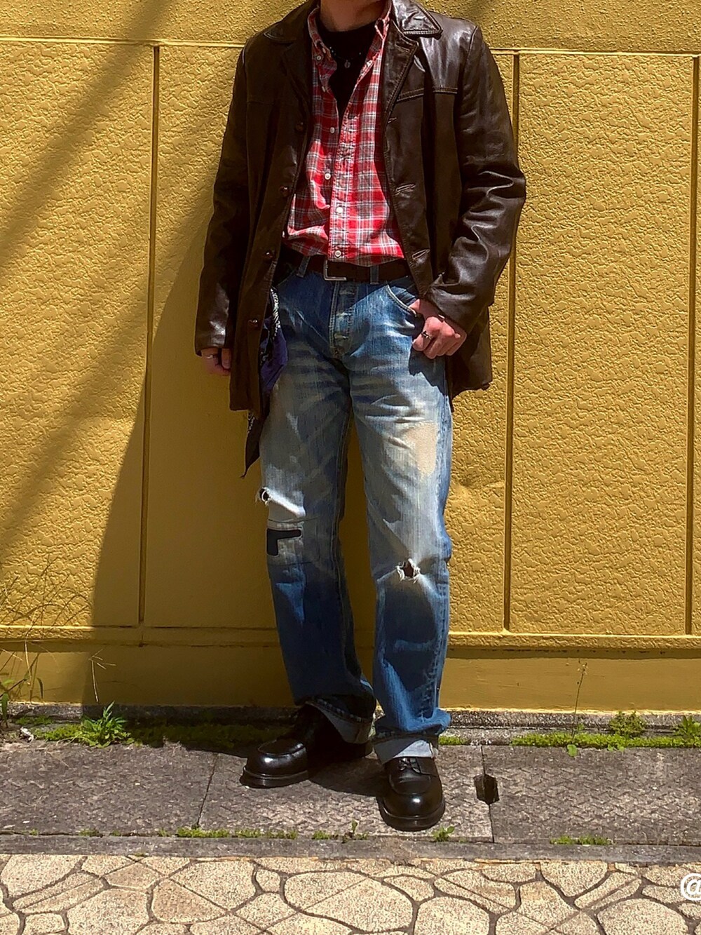 ブラック系のドレスシューズ、レッド系のトップス、ブルー系のデニムパンツを着用したメンズの春コーディネートの2枚目の写真