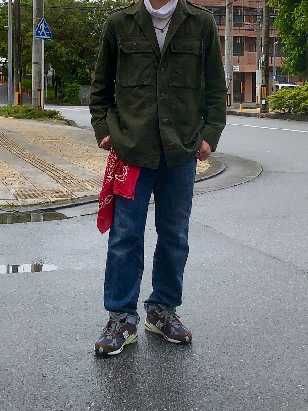 グリーン系のミリタリージャケット、ブラウン系のスニーカー、レッド系のトップスを着用したメンズの春コーディネートの2枚目の写真