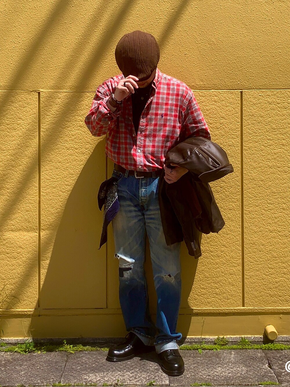 ブラック系のドレスシューズ、レッド系のトップス、ブルー系のデニムパンツを着用したメンズの春コーディネートの4枚目の写真