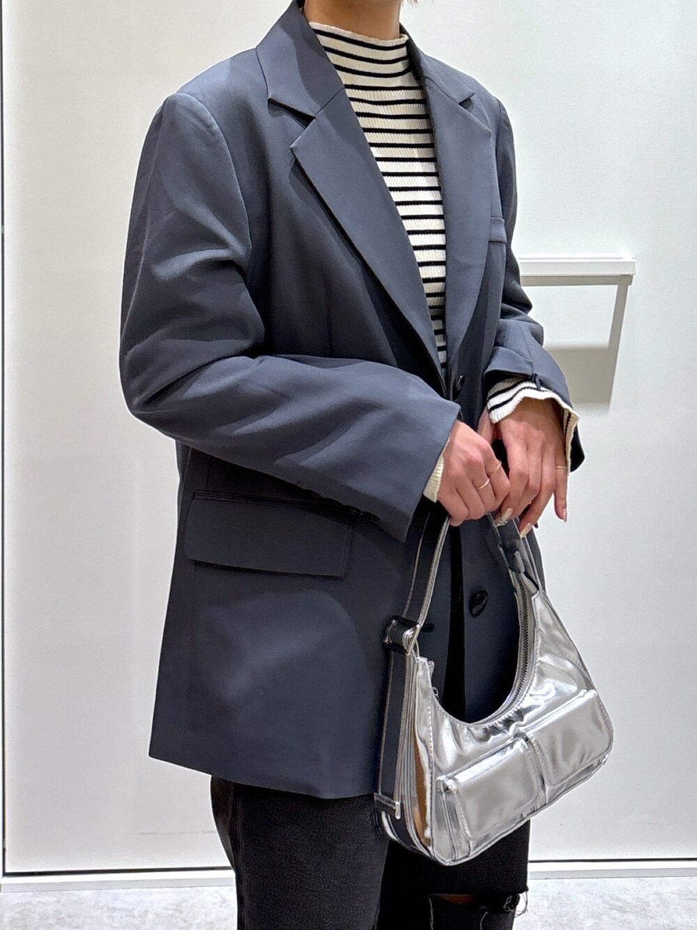 グレー系のテーラードジャケット、ホワイト系のニット/セーター、ブルー系のデニムパンツを着用したレディースの春コーディネートの3枚目の写真