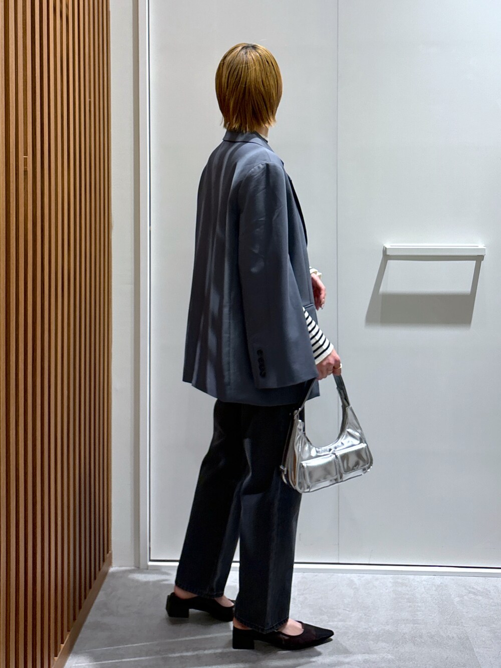 グレー系のテーラードジャケット、ホワイト系のニット/セーター、ブルー系のデニムパンツを着用したレディースの春コーディネートの2枚目の写真