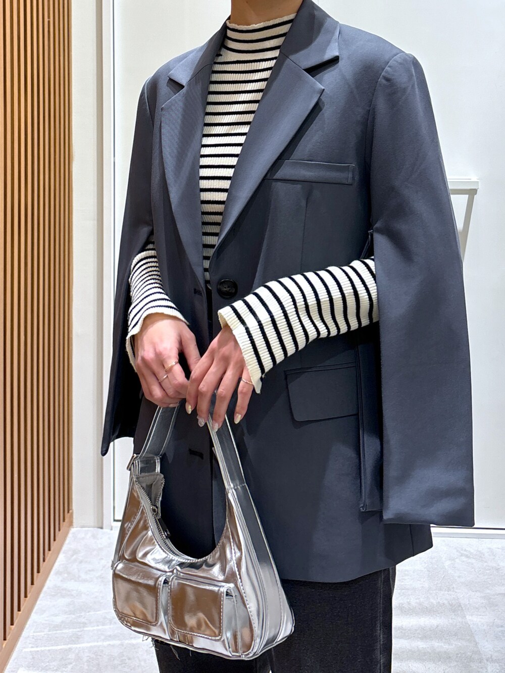 グレー系のテーラードジャケット、ホワイト系のニット/セーター、ブルー系のデニムパンツを着用したレディースの春コーディネートの4枚目の写真