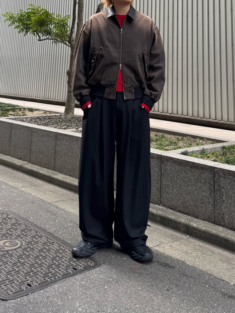 ブラック系のスラックス、ブラウン系のデニムジャケット、レッド系のニット/セーターを着用したメンズの冬コーディネートの2枚目の写真