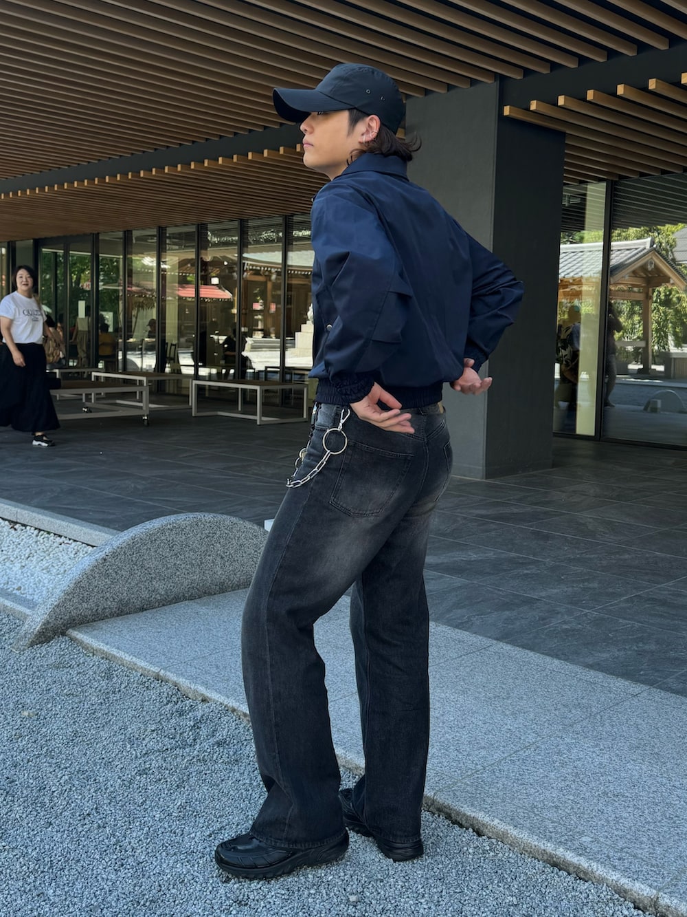 ブラック系のデニムパンツ、ブルー系のブルゾン、シルバー系のネックレスを着用したメンズの秋コーディネートの2枚目の写真