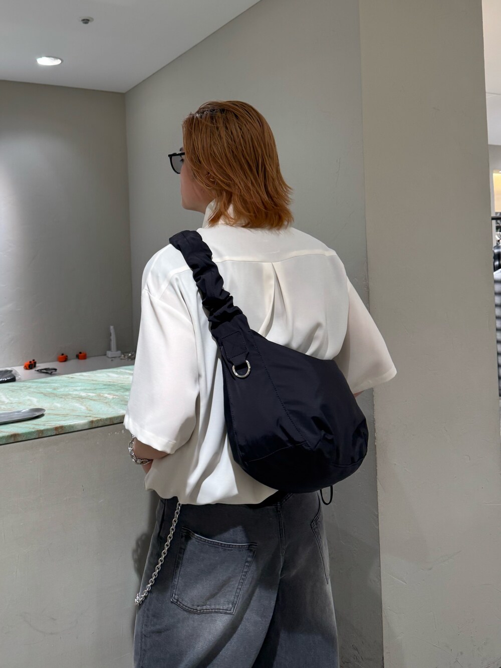 ブラック系のデニムパンツ、ブラック系のショルダーバッグ、グレー系のシャツ/ブラウスを着用したメンズの夏コーディネートの6枚目の写真