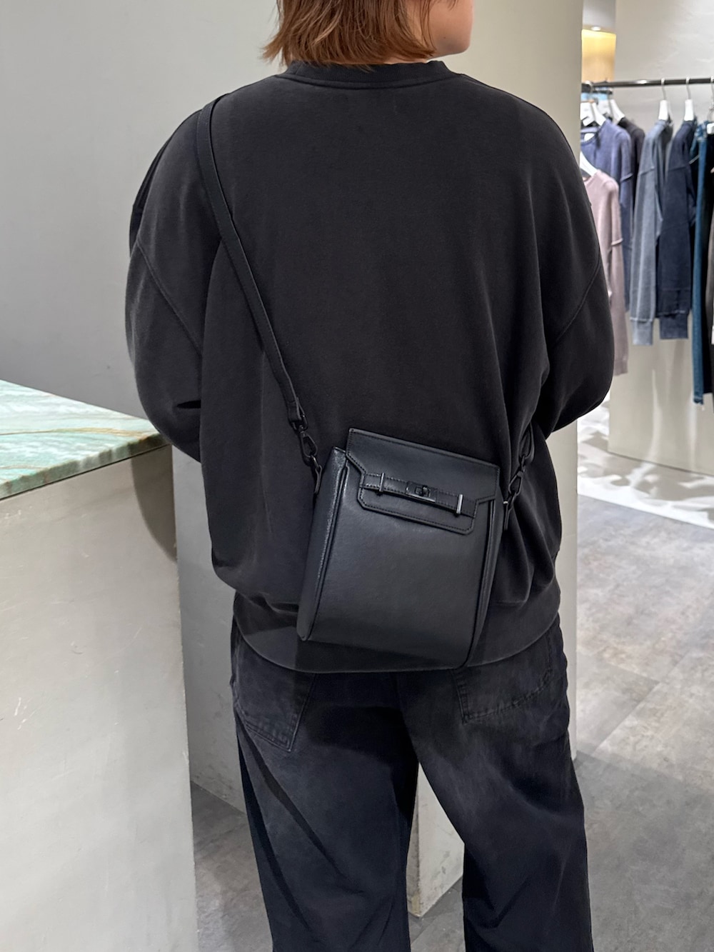 ブラック系のデニムパンツ、ブラック系のスウェット、ブラック系のショルダーバッグを着用したメンズの秋コーディネートの5枚目の写真