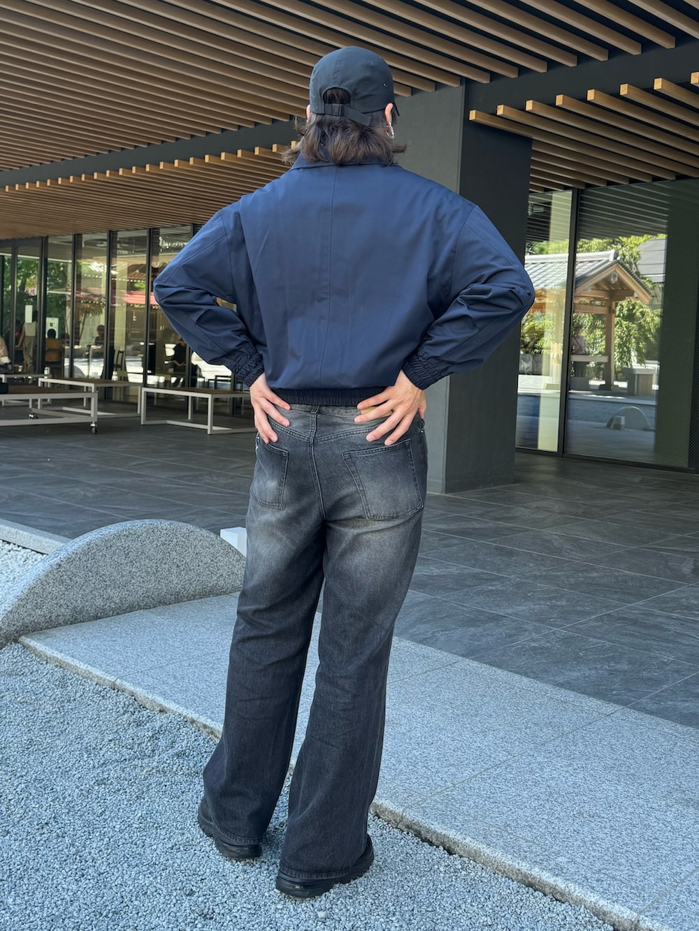 ブラック系のデニムパンツ、ブルー系のブルゾン、シルバー系のネックレスを着用したメンズの秋コーディネートの3枚目の写真