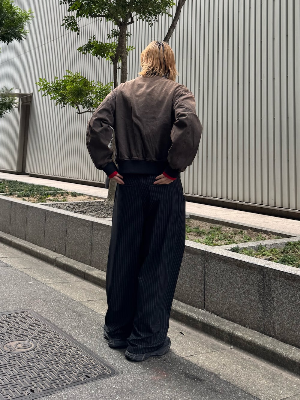 ブラック系のスラックス、ブラウン系のデニムジャケット、レッド系のニット/セーターを着用したメンズの冬コーディネートの3枚目の写真