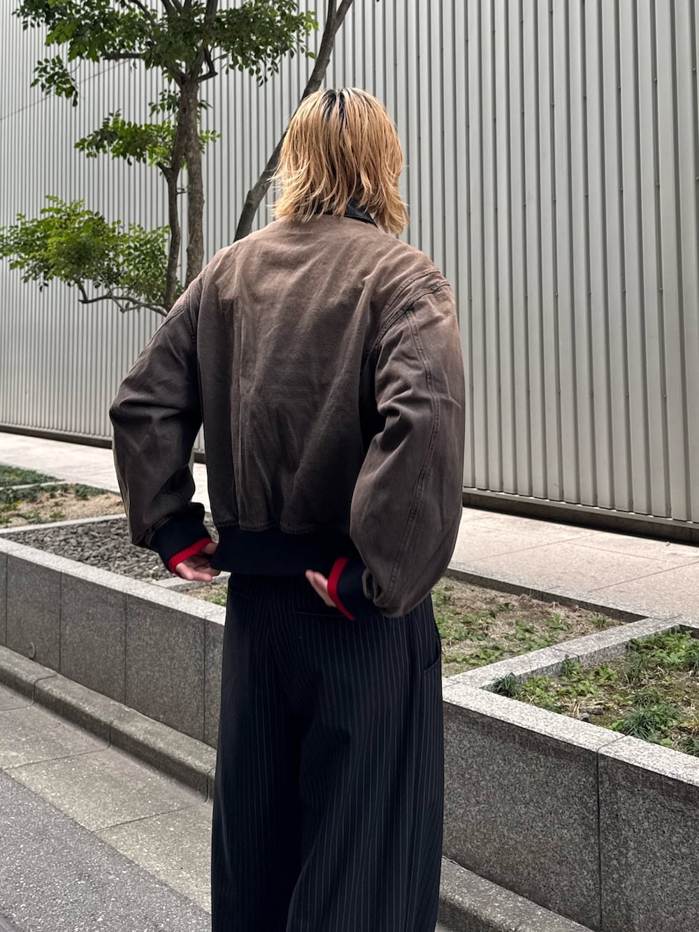 ブラック系のスラックス、ブラウン系のデニムジャケット、レッド系のニット/セーターを着用したメンズの冬コーディネートの5枚目の写真