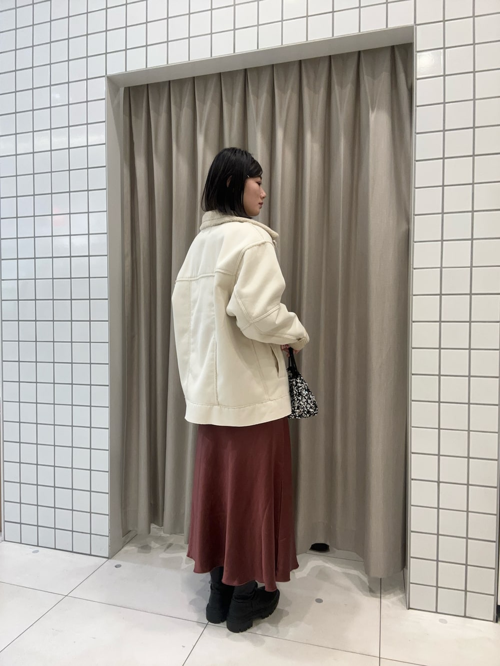 ホワイト系のニット/セーター、ブラウン系のスカート、シルバー系のハンドバッグを着用したレディースの冬コーディネートの2枚目の写真