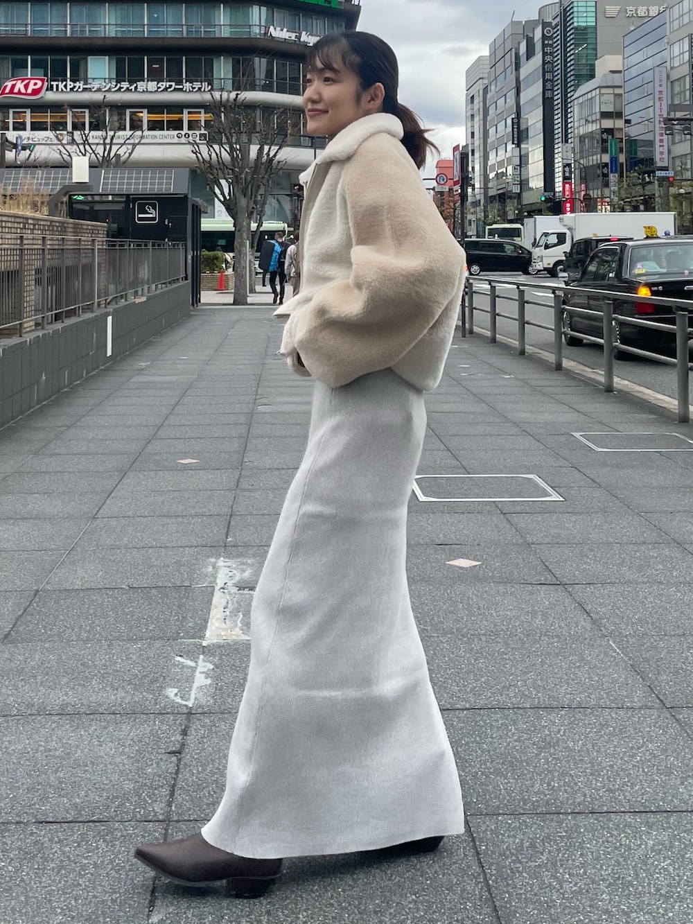 ホワイト系のブルゾン、オレンジ系のニット/セーター、グレー系のスカートを着用したレディースの冬コーディネートの2枚目の写真