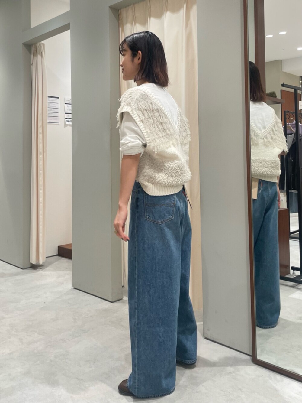 ホワイト系のベスト、ブルー系のデニムパンツ、ブラウン系のローファーを着用したレディースの春コーディネートの2枚目の写真