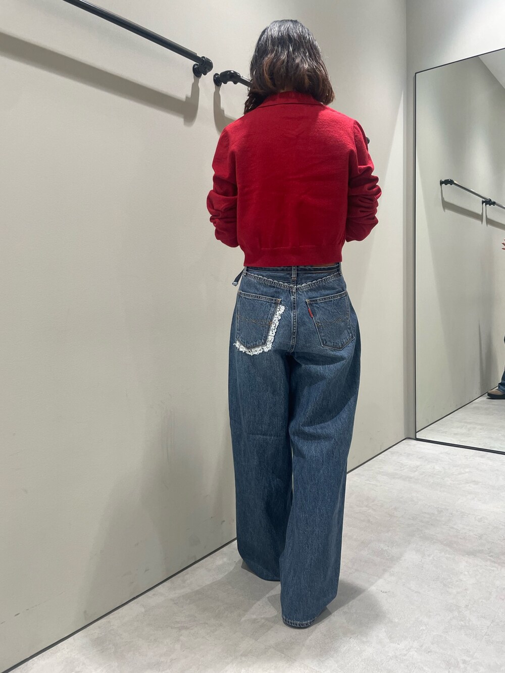 レッド系のカーディガン/ボレロ、ブルー系のデニムパンツを着用したレディースの秋コーディネートの3枚目の写真