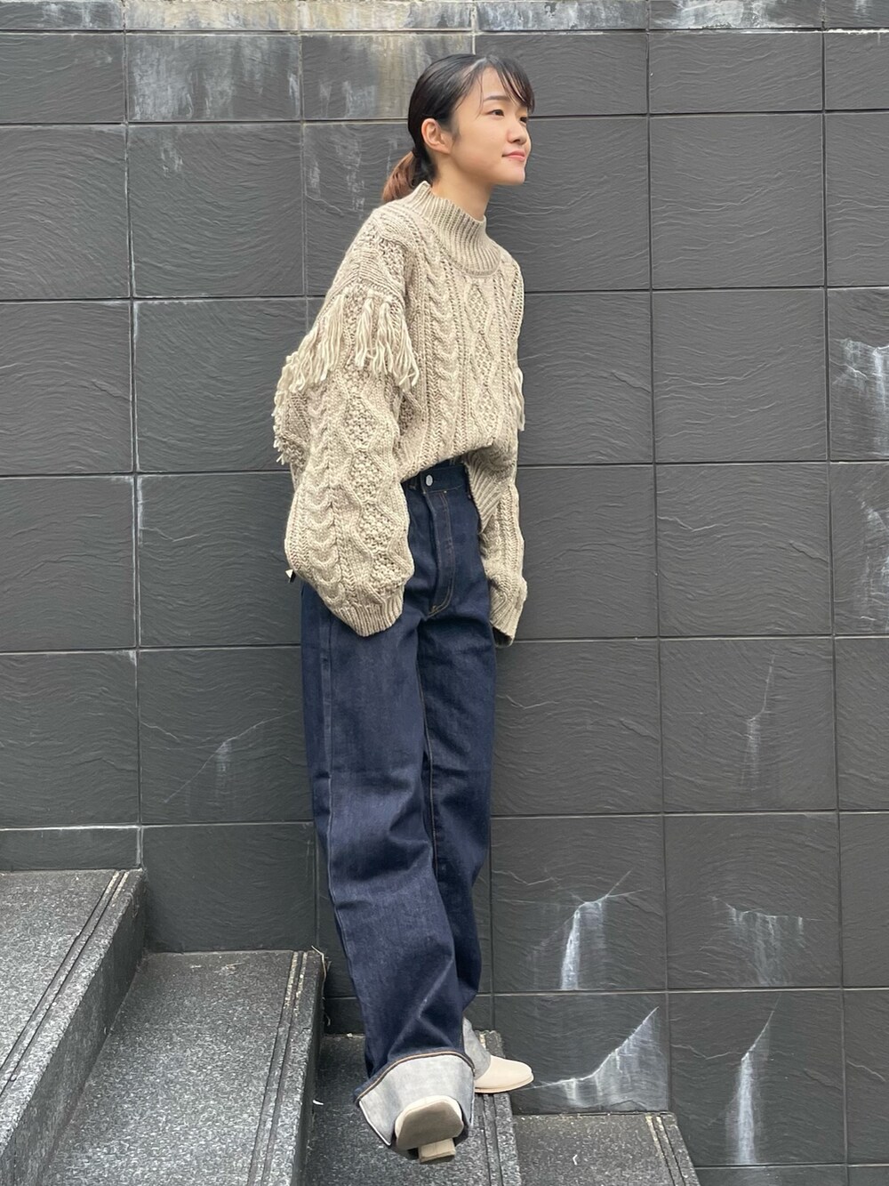 ベージュ系のニット/セーター、ブルー系のデニムパンツを着用したレディースの冬コーディネートの2枚目の写真