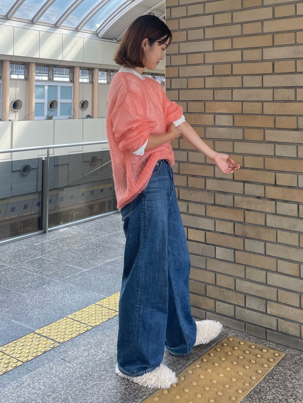 ピンク系のニット/セーター、ホワイト系のTシャツ/カットソー、ブルー系のデニムパンツを着用したレディースの秋コーディネートの2枚目の写真